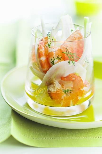 Креветки и фенхель веррин в стеклянной чашке над тарелкой — стоковое фото