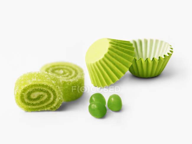 Bonbons roulés verts et tasses en papier sur fond blanc — Photo de stock
