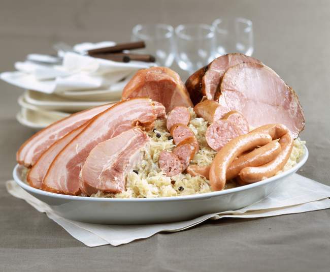 Closeup view of sauerkraut with sliced meat and sausages — Stock Photo