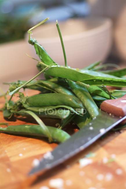 Casulos de ervilha na mesa com faca — Fotografia de Stock