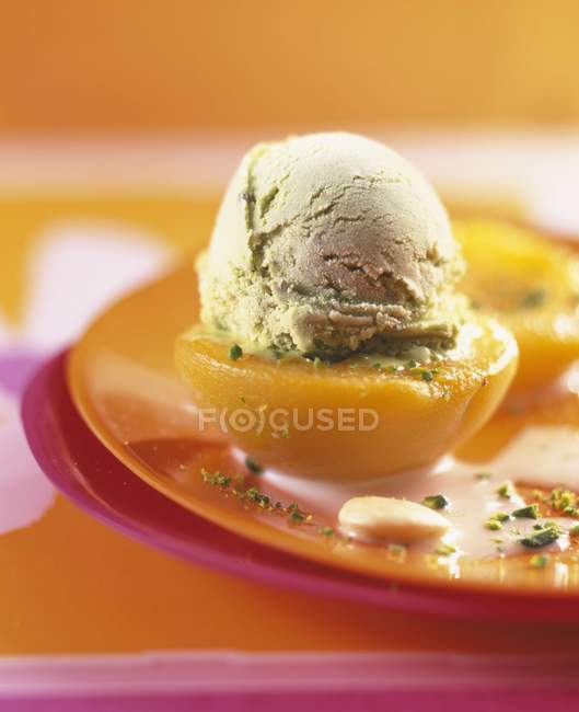 Durazno cubierto con una cucharada de helado de pistacho - foto de stock