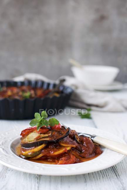 Ratatouille  on white plate with knife over wooden surface — Stock Photo