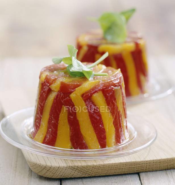 Red and yellow pepper terrines on glass plate over wooden desk — Stock Photo