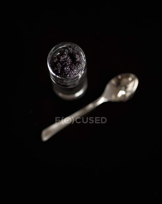 Œufs de poisson dans un verre de dégustation sur une surface noire — Photo de stock