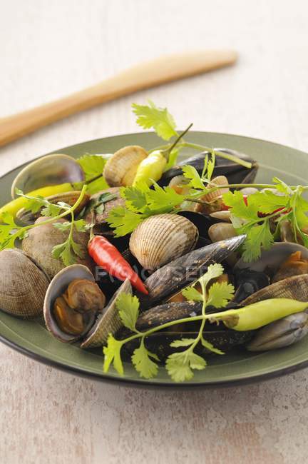 Shellfish with ginger and pimentos on green plate — Stock Photo
