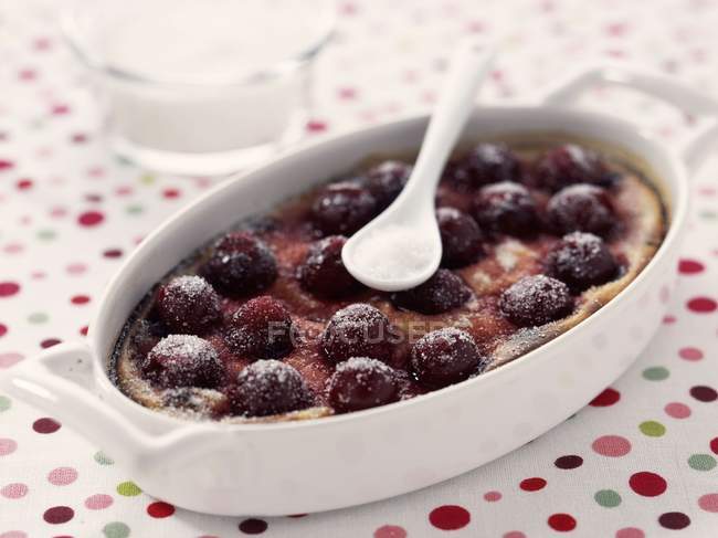 Closeup view of cherry clafoutis in baking dish with spoon — Stock Photo