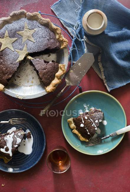 Vista superior del pastel de chocolate con nueces y pasas servidas en platos - foto de stock