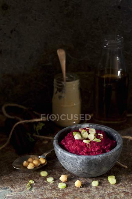 Red beet hummus in black bowl over wooden surface — Stock Photo