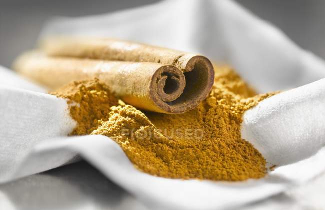 Closeup view of cinnamon stick and powder on white cloth — Stock Photo
