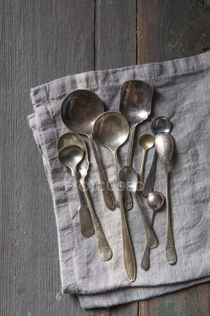 Vista dall'alto di cucchiai d'argento vintage su un tovagliolo di lino grigio — Foto stock