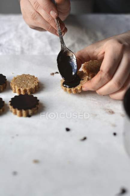 Closeup cropped view of person cooking raw vegan oat cookies with chocolate glaze — Stock Photo
