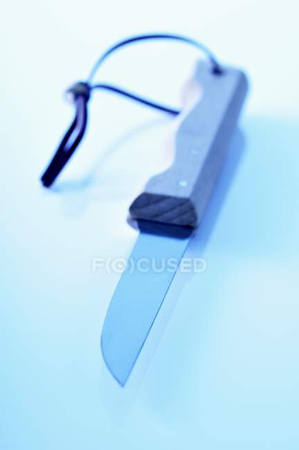 Вид крупным планом на один кухонный нож со шнурком на голубой поверхности — стоковое фото