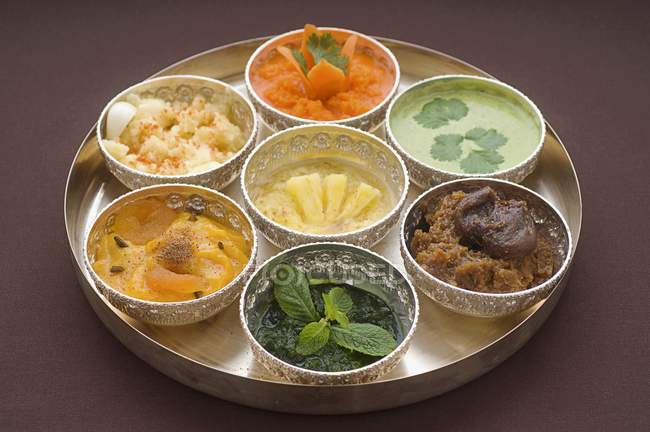 Tray of seven Indian chutneys over brown surface — Stock Photo