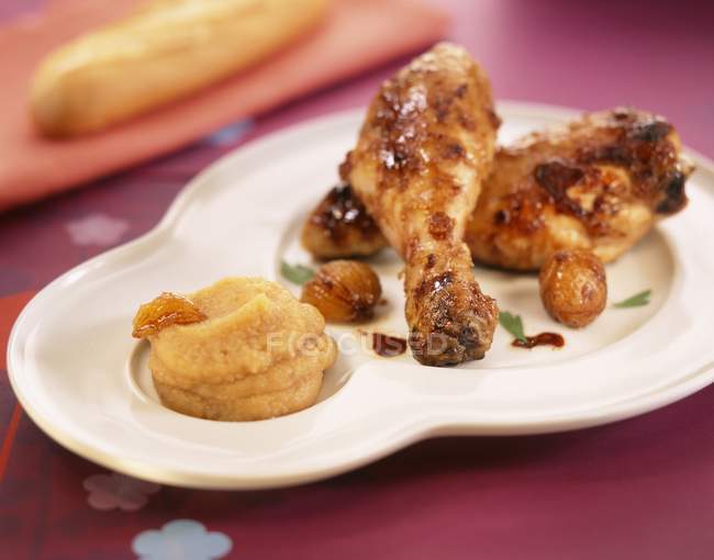 Крупный план жареных куриных ножек с ореховым пюре на тарелке — стоковое фото