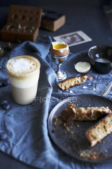 Vista elevada de huevo cocido, pan y café con leche - foto de stock