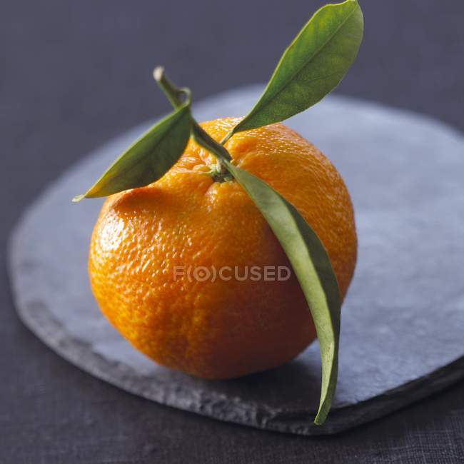 Mandarin with leaves on stone tray — Stock Photo
