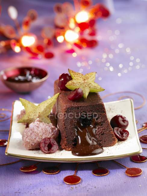 Vista de primer plano de pastel de chocolate Moelleux con fruta estrella y cerezas confitadas - foto de stock