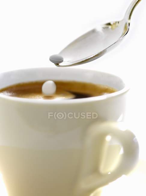 Adding artificial sweetener to cup of expresso — Stock Photo