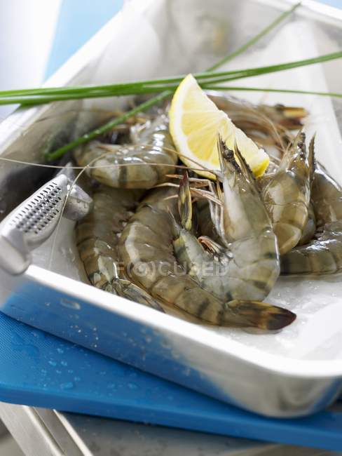 Raw prawns with wedge of lemon — Stock Photo