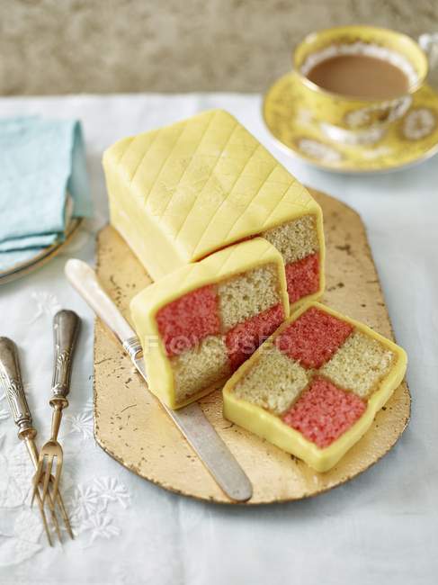 Closeup view of sliced Battenberg dessert with coffee — Stock Photo