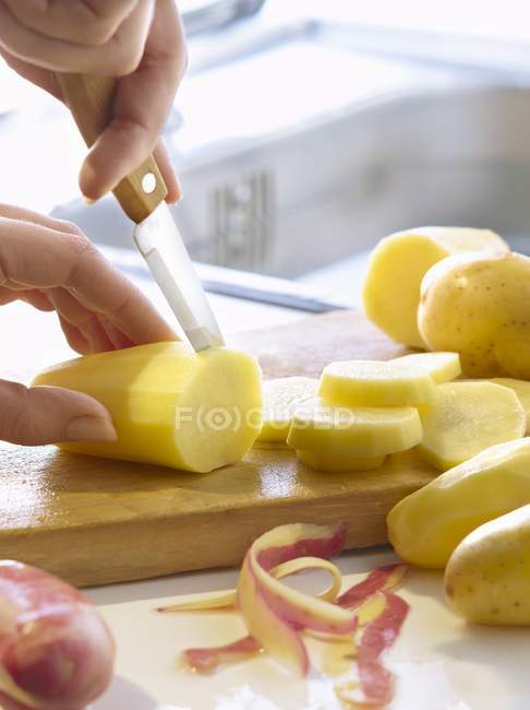 Weibliche Hände schneiden Kartoffeln — Stockfoto