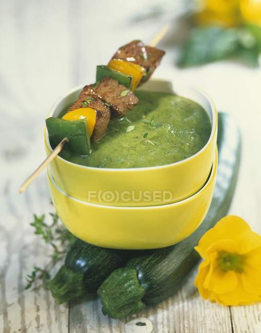 Cream of zucchini and pesto soup on wooden surface — Stock Photo