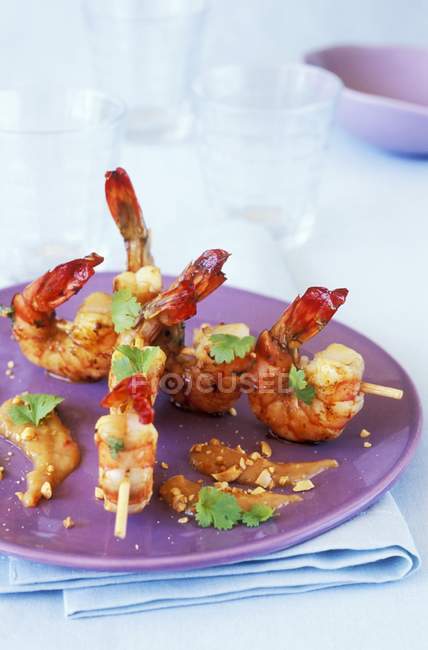 Espetos de camarão em prato roxo sobre toalha — Fotografia de Stock