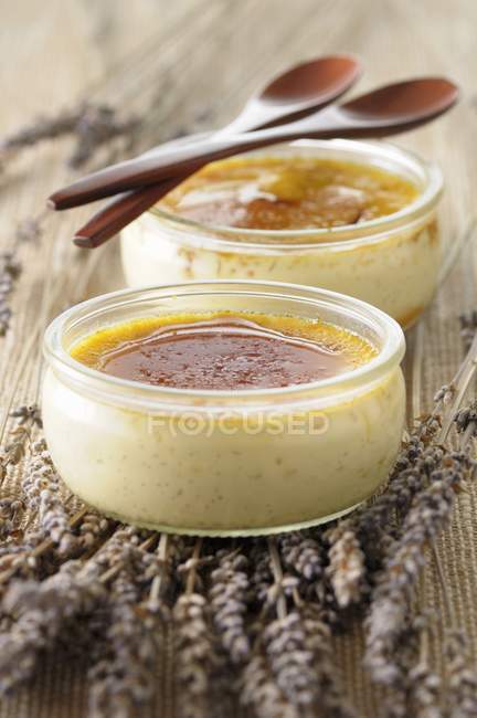 Spazzola Crme alla lavanda e vaniglia in vasi di vetro su superficie di legno — Foto stock
