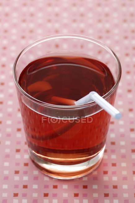 Closeup view of strawberry syrup with drinking straw in glass — Stock Photo