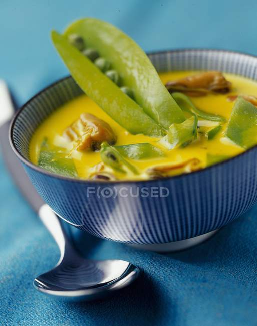 Mejillones al curry con crema y guisantes de azúcar en tazón azul - foto de stock