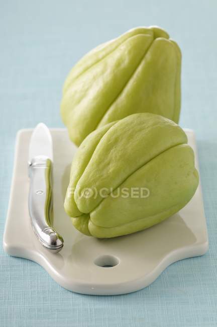Chayote squash on choppinh board with knife — Stock Photo