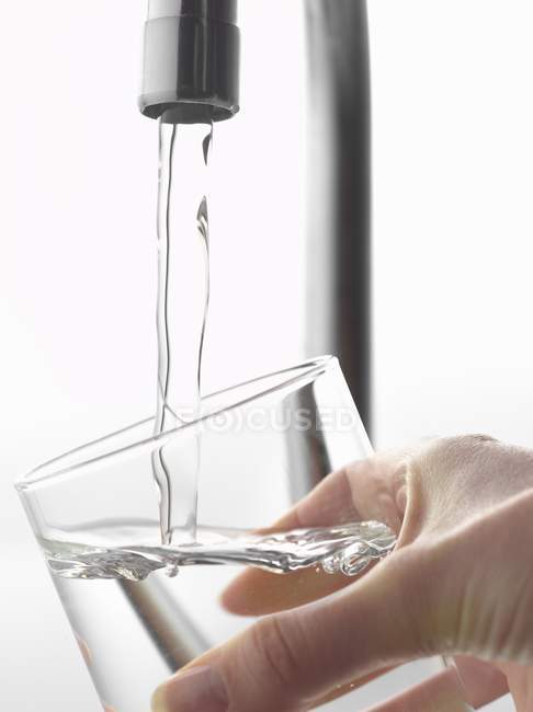 Наполнение стакана воды из крана — стоковое фото