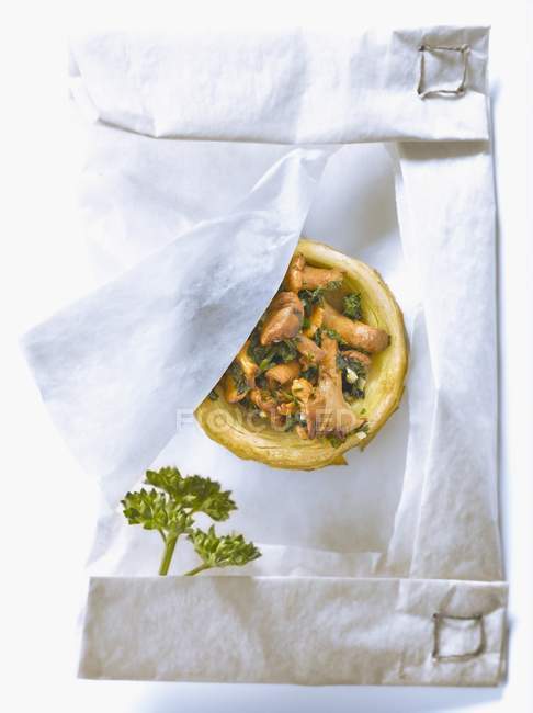 Base de alcachofa rellena de rebozuelos, perejil picado y ajo cocido en papel de cera - foto de stock