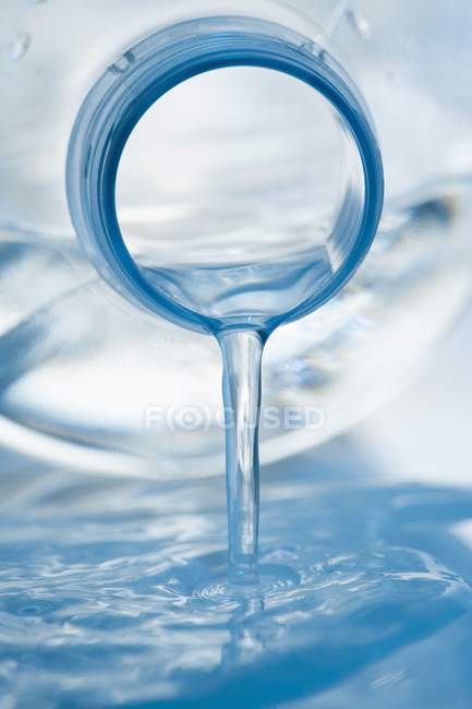Vista close-up de água que flui de uma garrafa de plástico — Fotografia de Stock