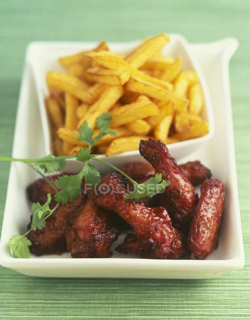 Closeup view of chicken drumsticks with French fries — Stock Photo
