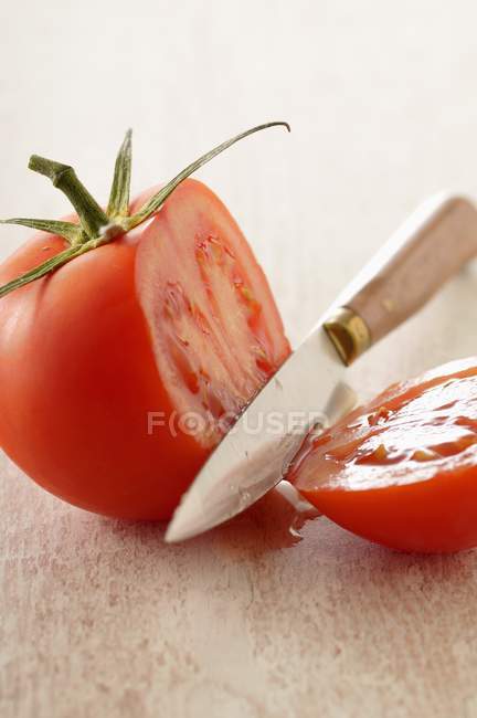 Tomate coupante avec couteau — Photo de stock