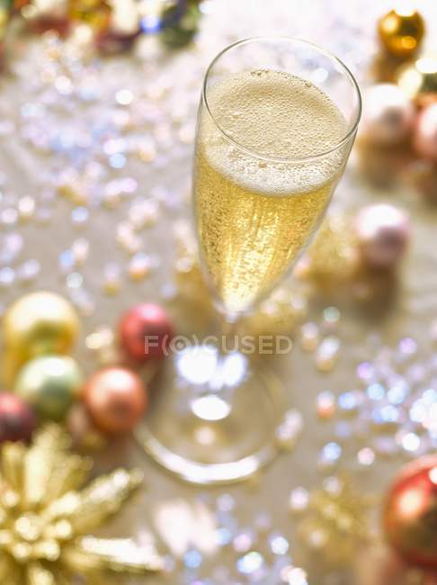 Copa de champán y decoraciones navideñas - foto de stock