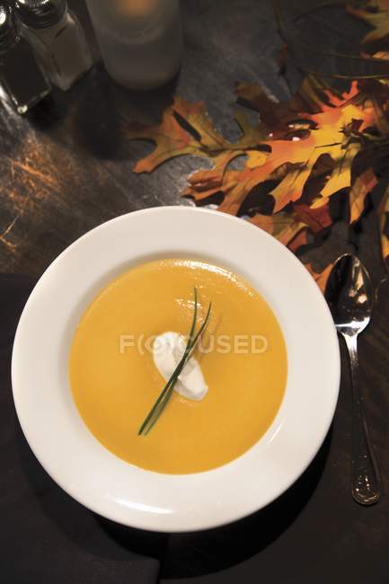 Ginger Yam Bisque in white bowl with autumn leaves  on white plate — Stock Photo