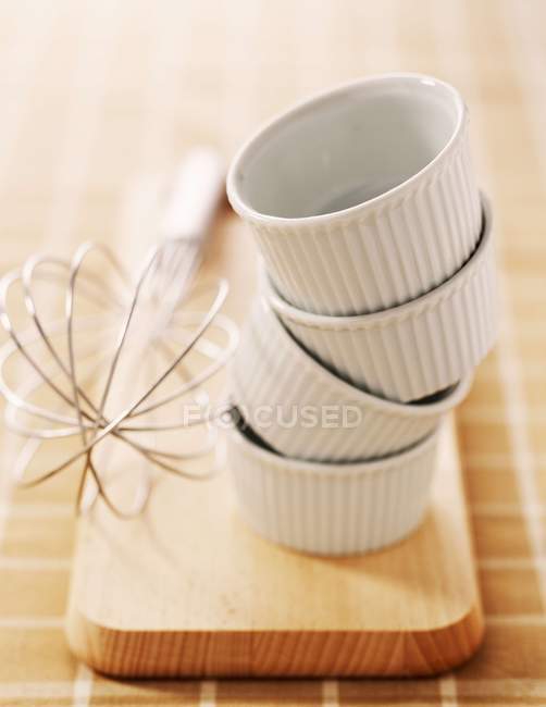 Closeup view of piled ramekins and whisk — Stock Photo