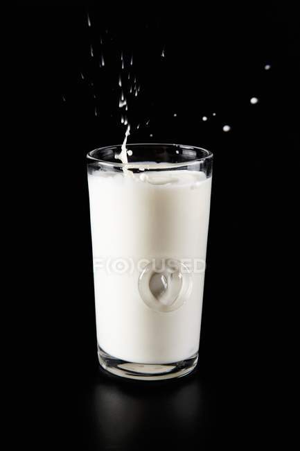 Glass of milk with splash — Stock Photo