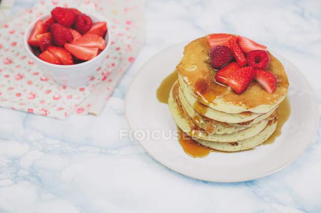 Closeup view of pancakes with raspberries, strawberries and maple syrup — Stock Photo