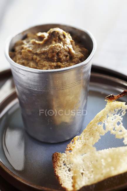 Eggplant caviar in metal cup over plate — Stock Photo