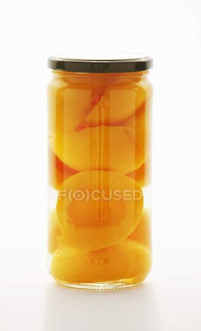 Closeup view of preserved peach halves in a jar — Stock Photo
