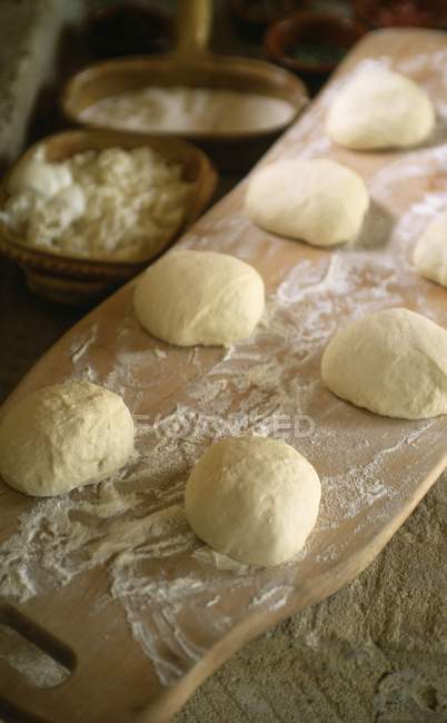 Closeup view of raw dough balls with flour on wooden board — Stock Photo