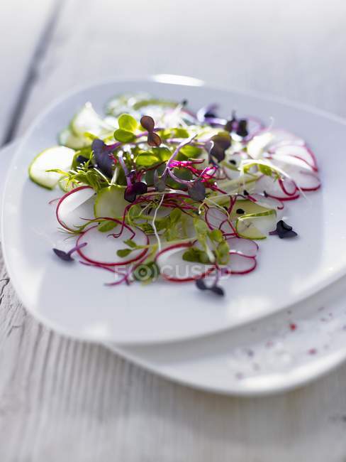 Radish Carpaccio on white plate over light wooden surface — Stock Photo