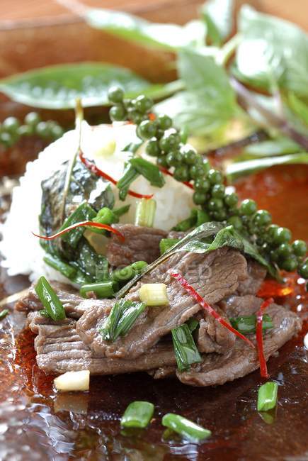 Жареное мясо с овощами и зеленым горошком на тарелке — стоковое фото