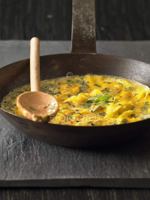 Closeup view of herbal omelette with spoon on frying pan — Stock Photo