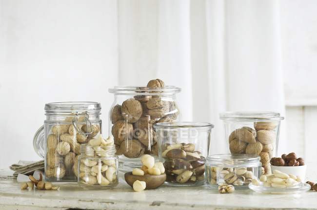 Various types of nuts in glass jars on a rustic kitchen table — Stock Photo