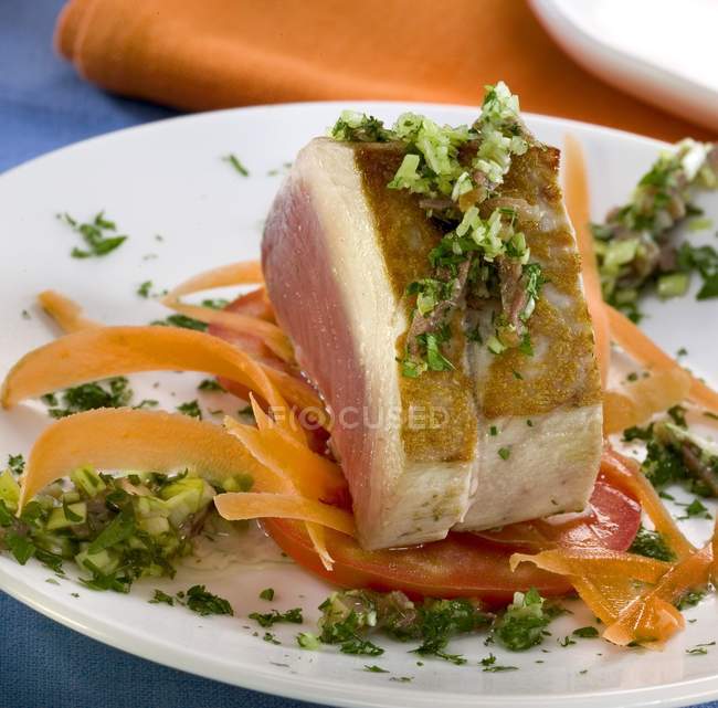Ломтик мяса с травами и овощами на белой тарелке — стоковое фото