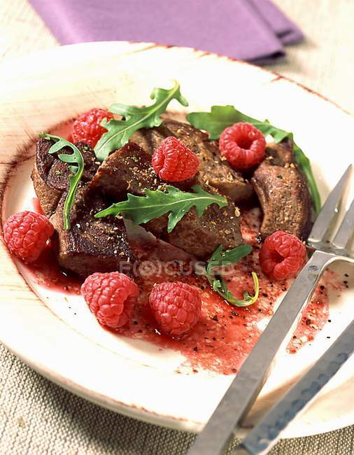 Closeup view of venison meat with raspberries and rucola on plate — Stock Photo
